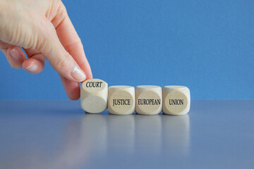 Hand turns a cube and form the acronym CJEU 'COURT OF JUSTICE OF THE EUROPEAN UNION' Beautiful blue background