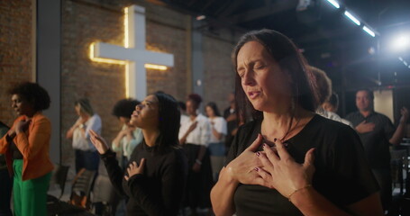 Diverse group in deep worship, hands on heart, glowing cross in background, collective spiritual connection, heartfelt faith, and unity in sacred church gathering