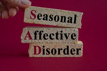 Brick blocks with words Sad-Seasonal Affective Disorder. Beautiful red background. Businessman...