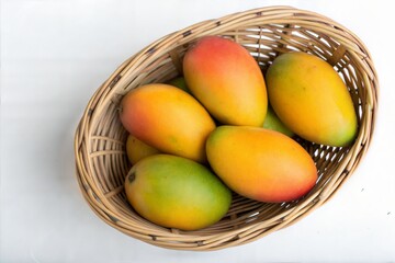 Top View of Ripe Mangoes in Wicker Basket on White Background