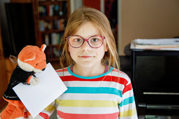 Little school girl holding a letter to a friend. Happy child writing to penfriend.