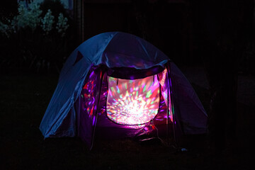 Tent with children inside glow in the night. Kids making overnight sleeping party in domestic...