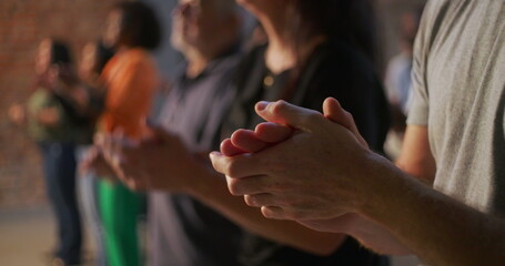 Close-up of diverse congregation clapping hands in unity during an uplifting worship session at a...