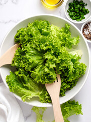 Crisp lettuce leaves in a bowl with wooden spoons and additional ingredients ready for salad mixing.