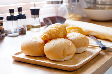 The croissant bread is placed on a wooden tray in the kitchen.