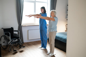 Elderly lady exercising with an instructor and looking involved