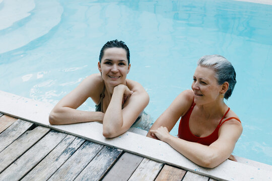Caucasian female adult and mature duo enjoying a relaxing pool day together