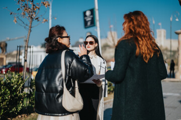 Three women discussing an outdoor business project, showcasing diverse perspectives, collaboration,...
