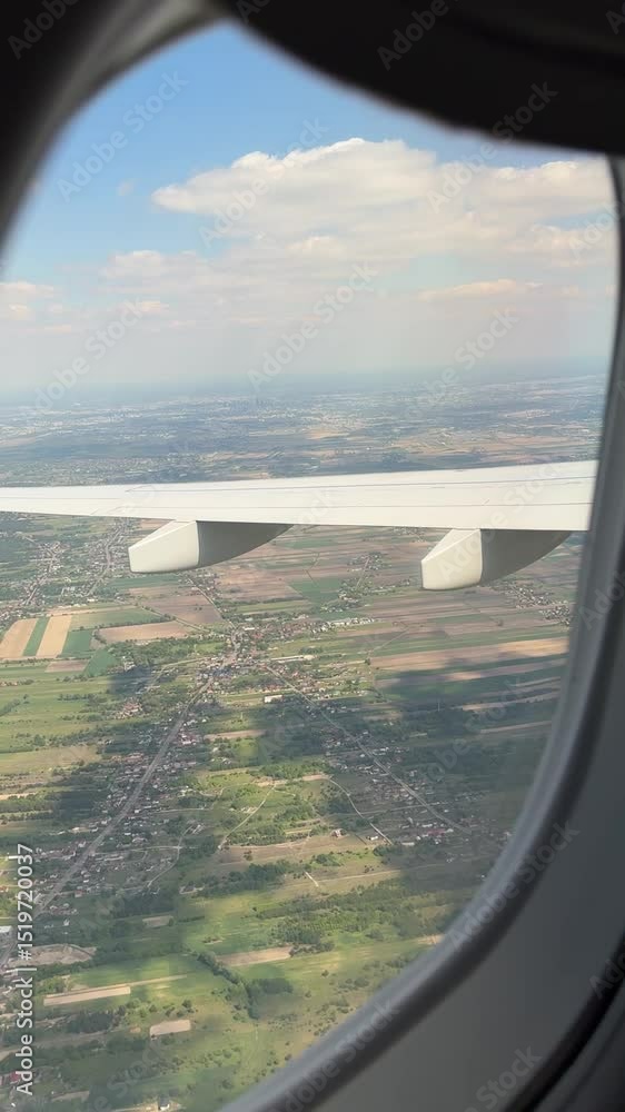 Poster Airplane wing view during descent over patchwork fields and suburbs in Poland
