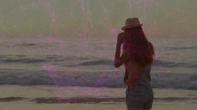Woman raising camera then lowering and lifting again while capturing ocean horizon for photography