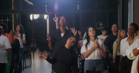 Group worship in a church setting, people standing in prayer, hands lifted, spiritual connection...