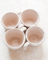Handmade unglazed ceramic cups in natural clay color on beige background. Artisan pottery with organic texture and minimalist aesthetic. Slow living and modern rustic style