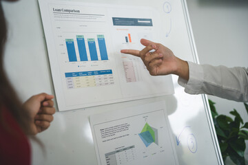 Business colleagues discussing loan comparison and financial data on whiteboard during a productive...