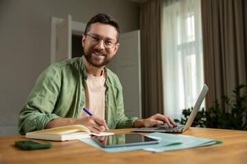 Obraz premium Bearded man analyzing reports in home office