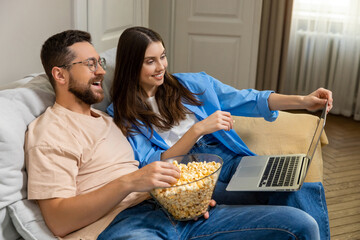 Family spending weekend at home enjoying popcorn and watching online comedy movie