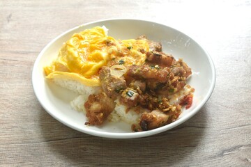 fried spicy crispy pork with chili and garlic topping plain rice dressing creamy egg omelette on plate