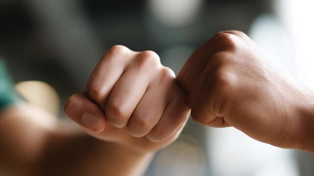 Close-up of two fists bumping in a gesture of camaraderie and friendship, symbolizing teamwork and support.

