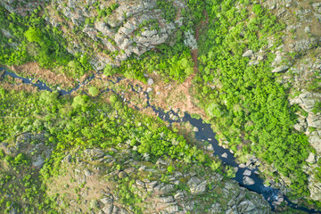 Aerial drone view of a mountain river cutting through a rocky canyon.