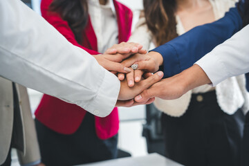 Business people stacking hands together, demonstrating teamwork, collaboration, and support in a...