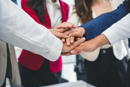 Business people stacking hands together, demonstrating teamwork, collaboration, and support in a united effort towards shared goals