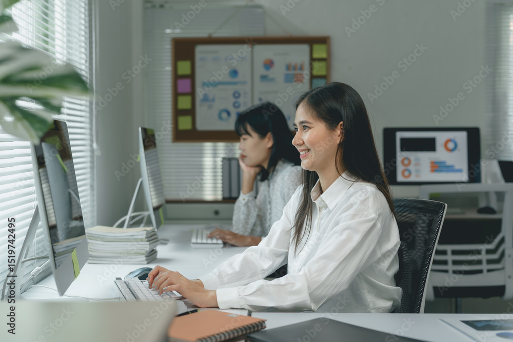 Poster two smiling businesswomen using desktop computers in a bright office, collaborating on a project and