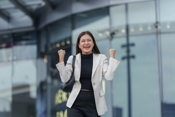 Young Asian manager celebrating joy and excitement outdoors, expressing happiness after achieving a...