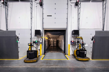 Interior of warehouse loading dock, with truck parked loading and two electric fork lifts on each side