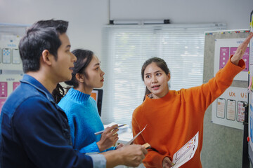 Young creative team of asian ux ui designers working together discussing mobile app interface...