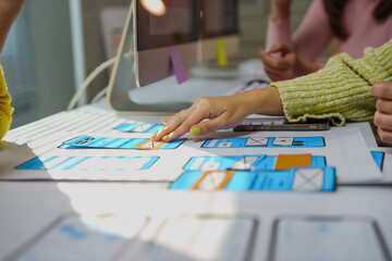 Web designers collaborating in an office, sketching mobile app layouts and discussing innovative strategies during a productive meeting