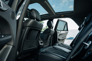 Modern luxury SUV interior with black leather rear seats and panoramic sunroof view – elegant...
