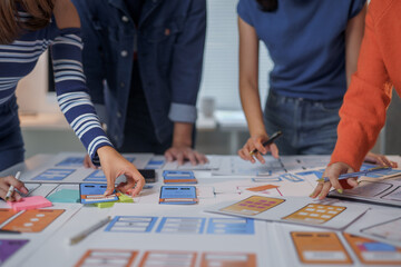 Fototapeta premium User experience designers are working on a new mobile app using sticky notes and pen on a large desk