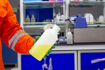 Close up worker and in protective gear holding chemical PH  buffer solution liquid in laboratory....