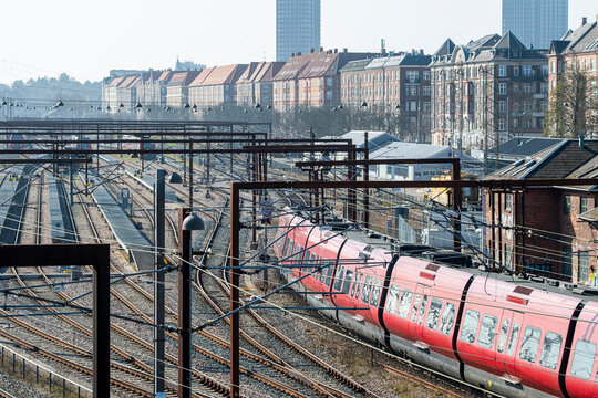 Copenhagen commuter train moving through a dense web of elevated rails and poles, combining movement, architecture and cityscape from above with commercial clarity.
