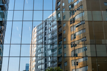 High-rise residential buildings mirrored on modern glass wall in Mexico City, captured from street level with urban density and light geometry for commercial design themes.