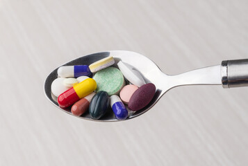 Assorted medication pills in a spoon. Supplements and ultra-processed food