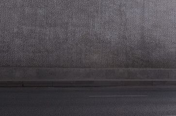 a gray concrete wall and an asphalt road