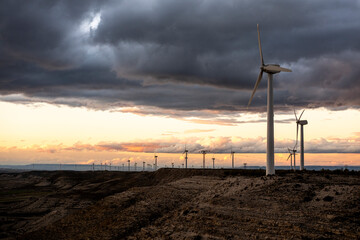 Sunset over wind farm in Zaragoza with clean ground line and atmospheric sky, excellent for sustainable themes and design applications with open space.