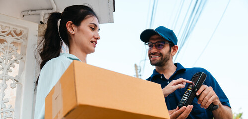 A woman receives a package and scans it to pay the delivery man during rush hour outside her house.