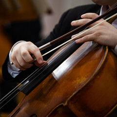A fragment of a cello in the hands of a musician in an orchestra