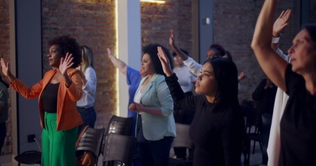 People raising hands in worship during a spiritual gathering in a church, expressing faith,...