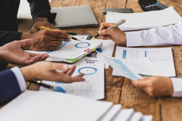 Business people analyzing financial documents around table. Business professionals collaborate, analyze financial data, and plan investments in office.