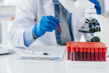Scientist analyzing blood sample using microscope in laboratory. Scientist in gloves examines a blood sample under a microscope in a lab, discovering medical mysteries.