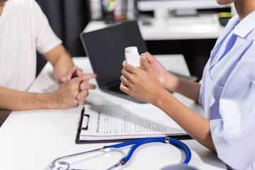 Female doctor examine the symptoms of male patients to provide advice on drug treatment and health care by experts. The pharmacist is explaining how to use the medicine.