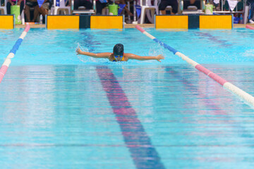 Naklejka premium Swimmer child swims butterfly swimming style in a race swimming pool. Water sports and competition, learning to swim classes for children.