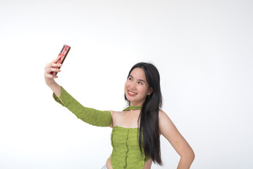 Young Filipino woman poses confidently with a smile while taking a selfie, radiating charm and...