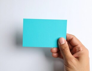 Fototapeta premium Hand Holding a Blue Rectangle Piece of Card Stock on a White Background.