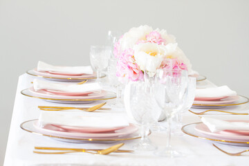 Elegant wedding table setting with pink peonies, gold cutlery, and crystal glassware, creating a romantic and sophisticated atmosphere.