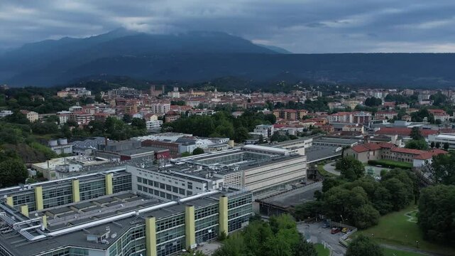 Modern glass-and-steel ICO IV building in Ivrea's Unesco-listed Olivetti district, framed by the Alps and Mount Mombarone in the background, drone shot, slow motion, 