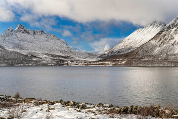 on tour of the island of Senja. Steep mountains in winter, snowy landscape on the shore of...