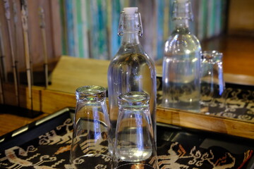 Glass Water Bottle and Two Upside-Down Glasses on Traditional Indonesian Tray